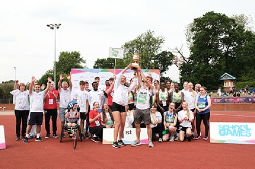 A group of athletes at the 2022 School Games National Finals celebrate and hold a trophy aloft