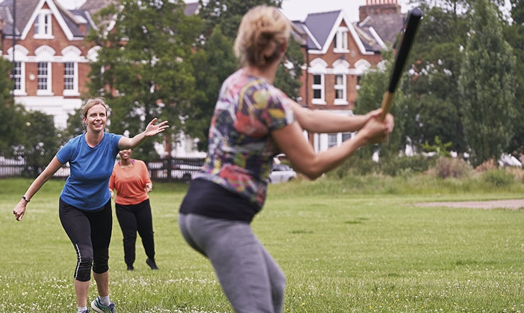 Women playing a game of rounders in a park