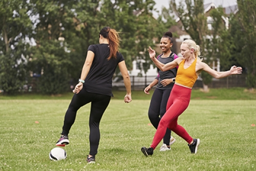 A group of women playing football in a park.