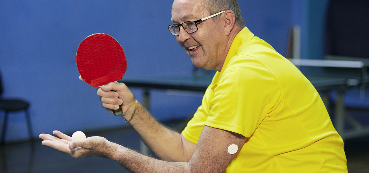 We Are Undefeatable case study Simon, plays table tennis in his wheelchair, with a blood glucose monitor patch on his arm