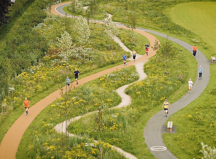 An overhead view of meandering multi-use paths through a landscaped park, with people running and walking on them.