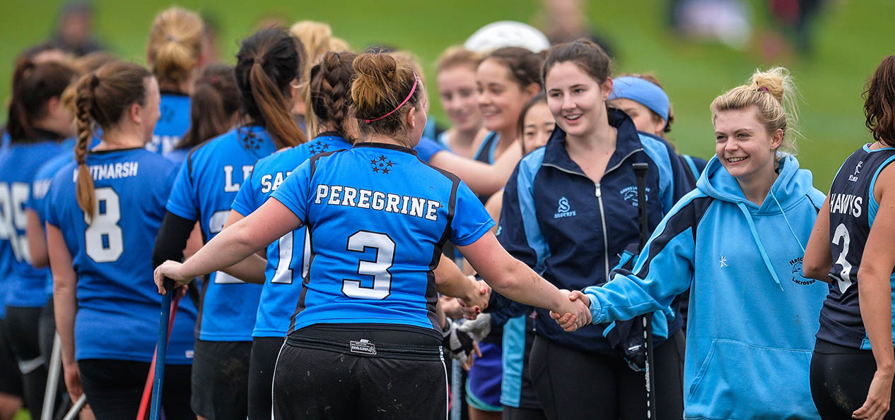 A group of lacrosse players shaking hands after a game.