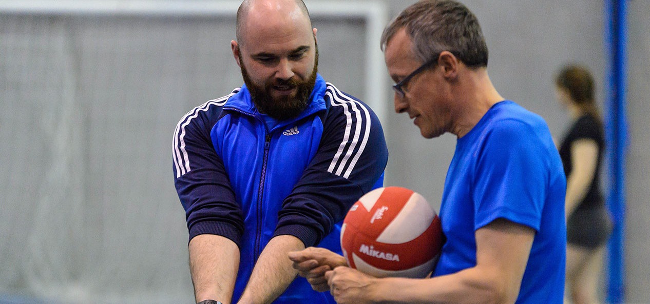 A volleyball coach demonstrates the technique for a dig shot.