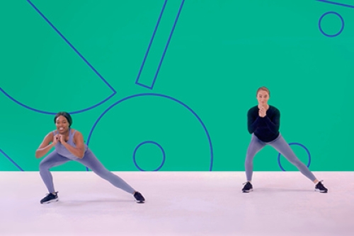 Two girls perform side lunges in an exercise class as part of a Studio You video