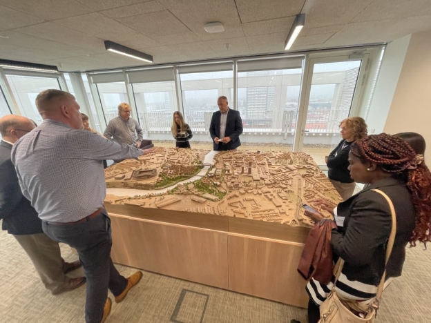 People gather round a large 3D designed model of a town during a workshop.