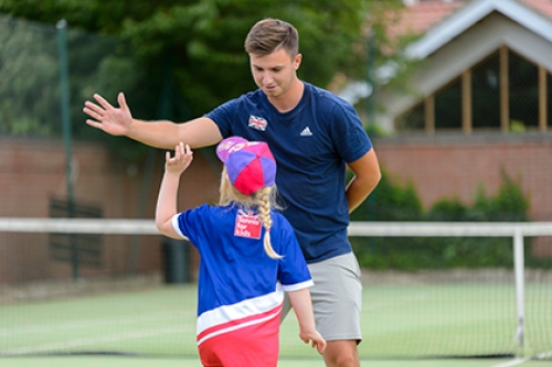 A tennis coach high-fives a girl during a coaching session.
