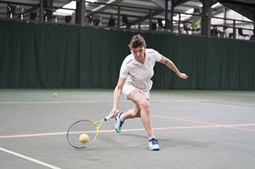 A visually impaired woman plays tennis.