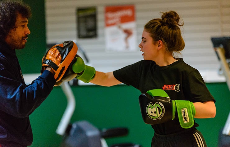 A girl boxing inside a sports hall.