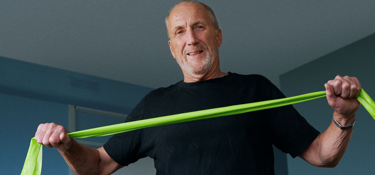 A man performs exercises at home using a resistance band.