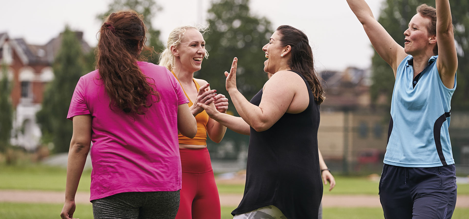 A group of women celebrating and high-fiving on a playing field