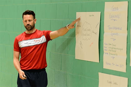 A man who works in sport pointing to a poster