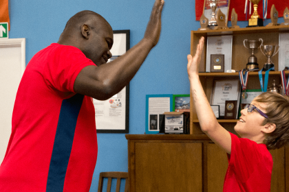 Child and coach high five during table tennis game