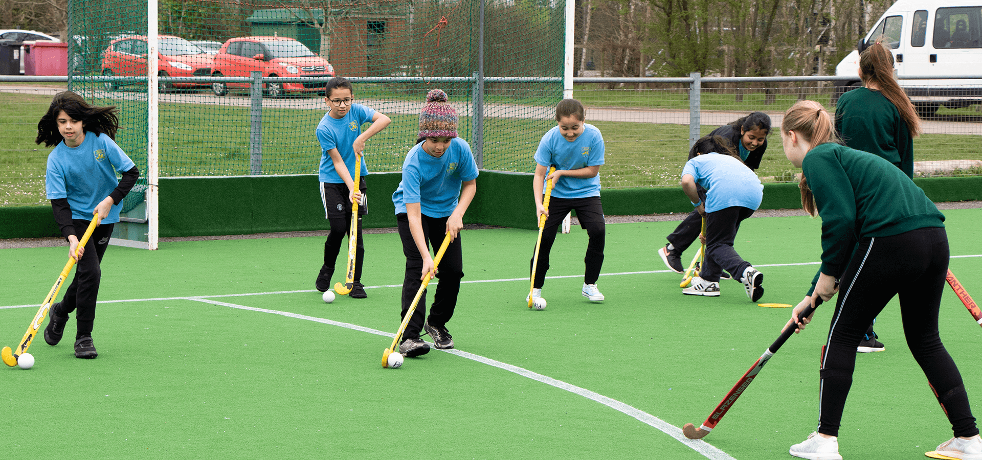 Children playing hockey on outdoor artificial pitch 