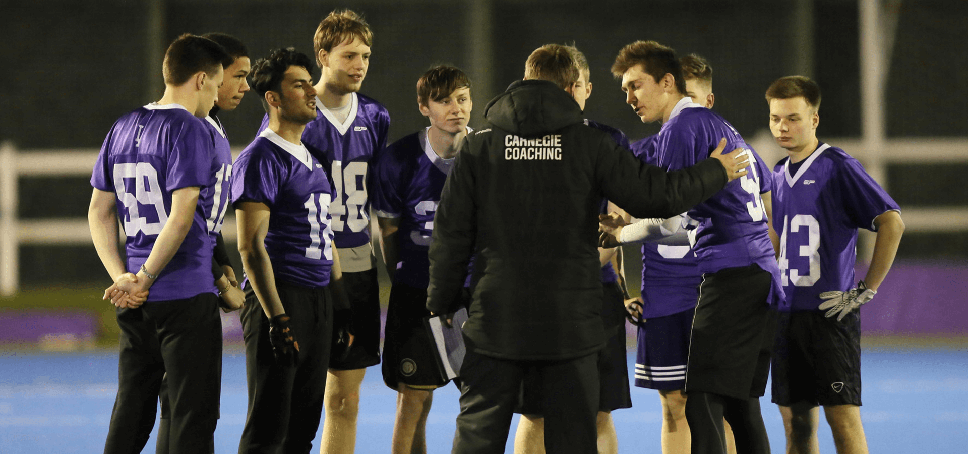 Coach talking to football players on pitch