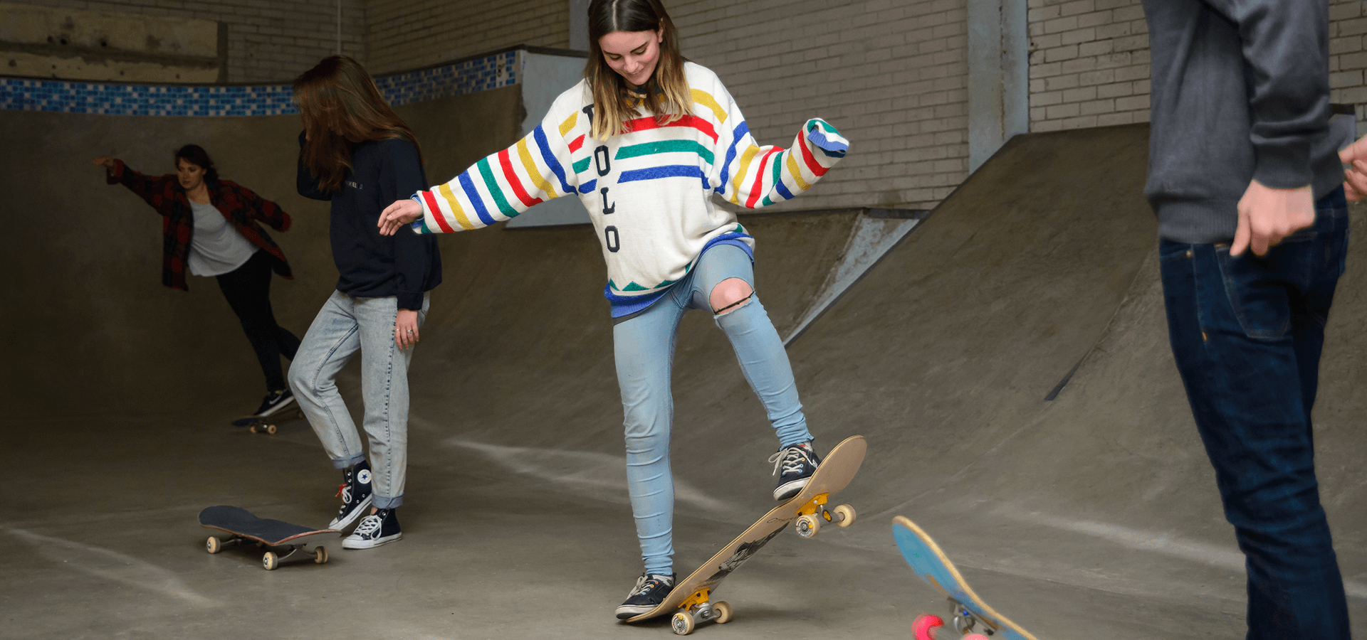 Girl learning to ride skate board in skate park