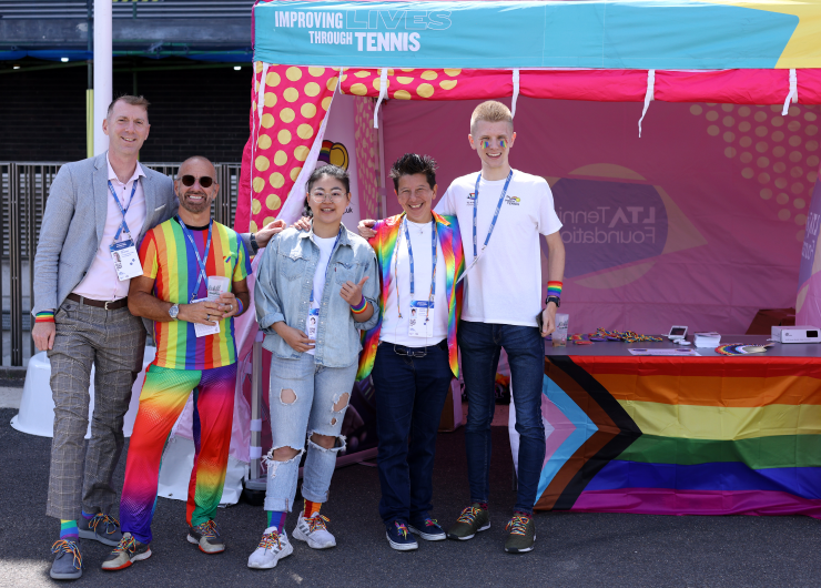 Pride in Tennis members pose for a photo in front of a colourful marquee at a tournament in Eastbourne