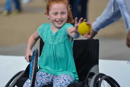 Young girl in wheelchair receiving ball